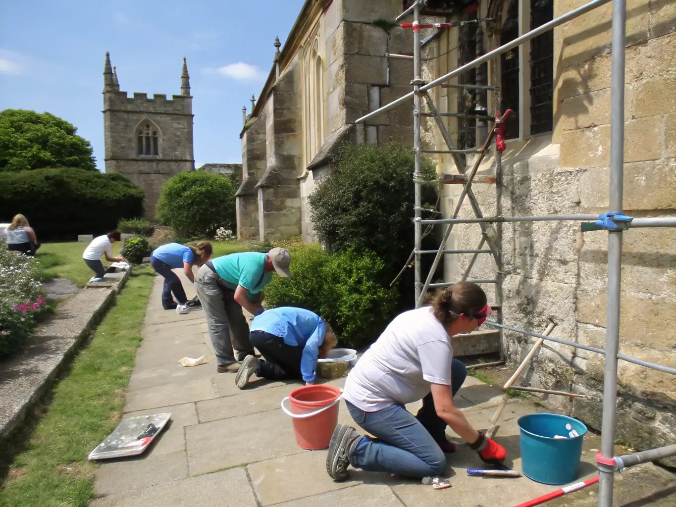 A group of volunteers working together to restore an old stone wall in Saléon, showcasing community involvement in heritage preservation.